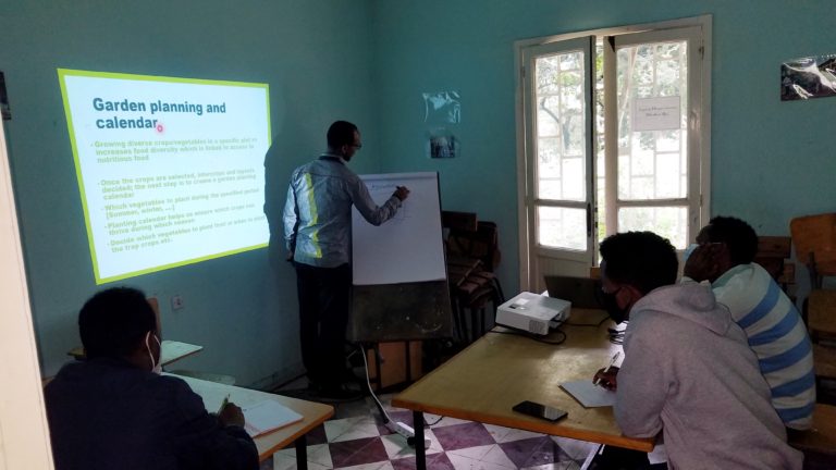 Teacher writing on a board about gardening for students